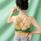 Back view of a model in a green bra top with thin yellow straps crossing over the shoulder blades