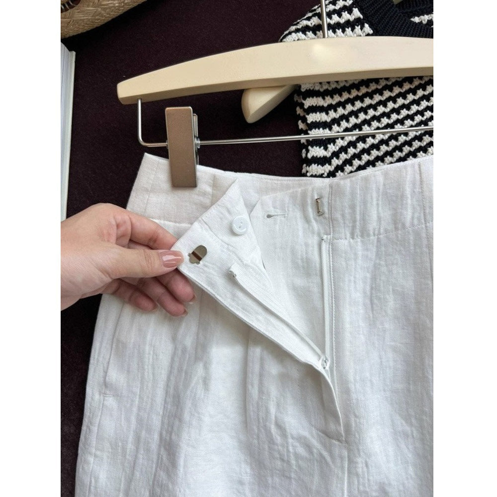 Hand holding open the front fly of white linen shorts showing button hook and zip