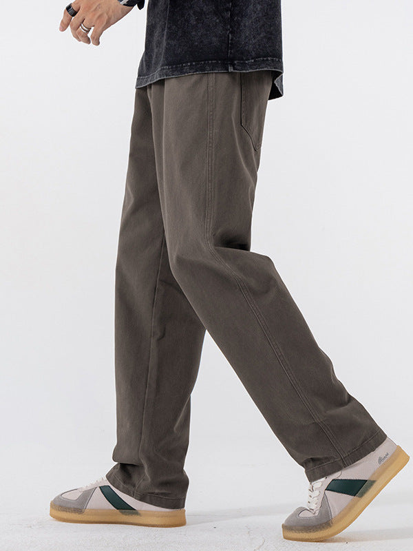 Dark gray straight leg cotton pants seen mid stride with white and green sneakers