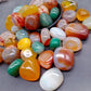 Smooth violet banded agate tumbled stones on a grey studio surface
