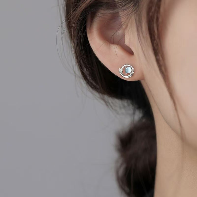 Moonstone-look planet stud shown on the lobe with its open orbital ring and single clear accent stone