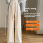 Cream high-waisted wide-leg drawstring pants worn with a gray cardigan and slippers, full length front view