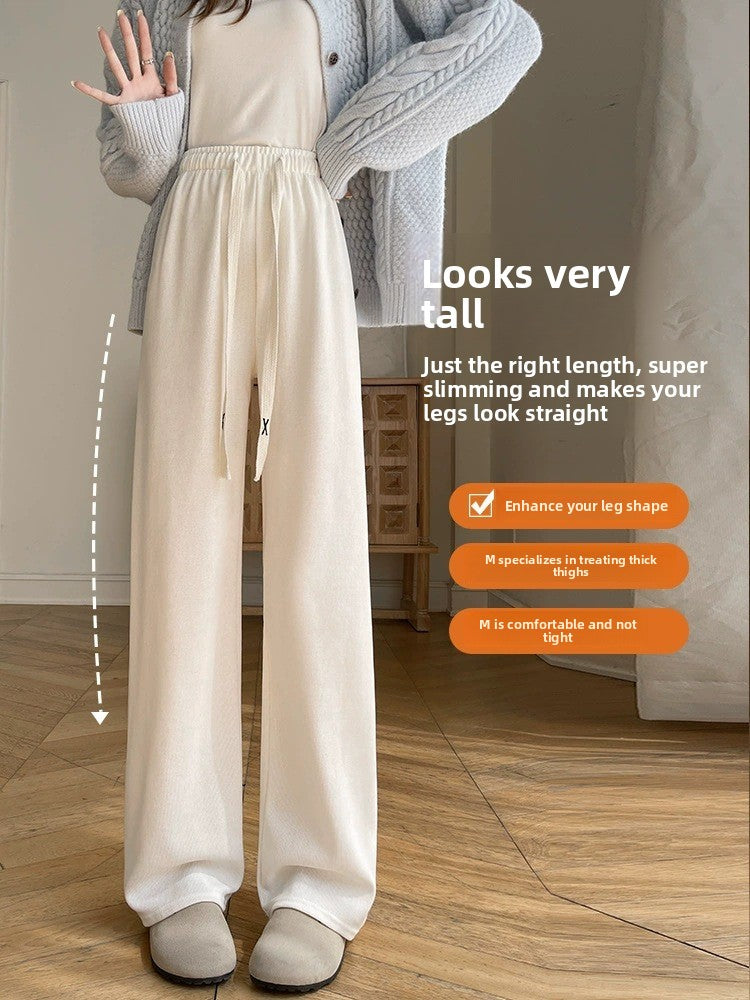 Cream high-waisted wide-leg drawstring pants worn with a gray cardigan and slippers, full length front view