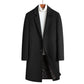 Black single-breasted long coat with notch lapel on a hanger over a white turtleneck, front view