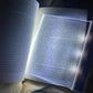 Cool white glow spread across a full page spread by the reading panel