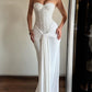 Woman in a white strapless long dress with a sequin bodice and draped skirt beside a mirror