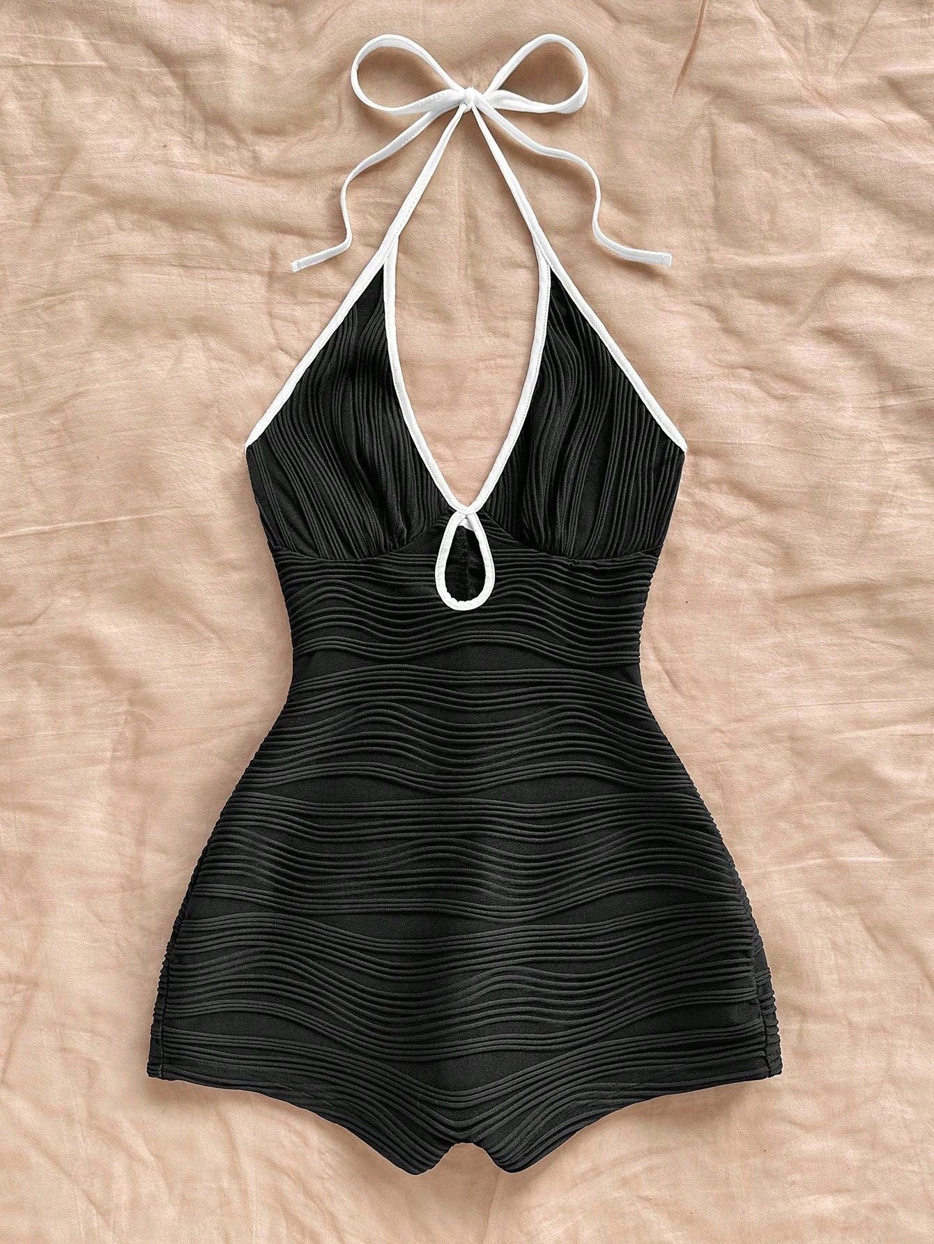 Halter neck bodycon romper in black rippled stretch fabric with a self tie bow and keyhole cutout