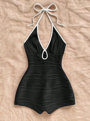 Halter neck bodycon romper in black rippled stretch fabric with a self tie bow and keyhole cutout