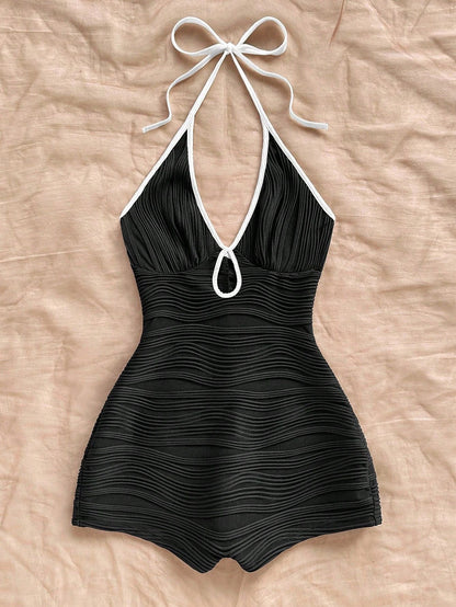 Halter neck bodycon romper in black rippled stretch fabric with a self tie bow and keyhole cutout