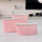 Three piece set of reusable pink silicone food storage bags standing sealed