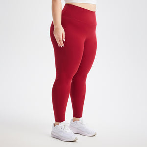 Deep red high waist leggings worn with white sneakers, three quarter side view showing the wide waistband