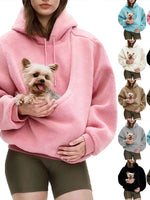 Woman wearing a pink plush fleece hooded pet pouch sweatshirt holding a small dog in the front pouch