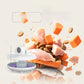 Exploded view of the cat feeder showing the domed top, central column and six compartment tray above scattered cat food