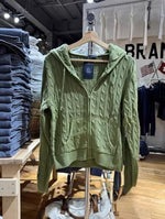 Avocado green cable knit zip up hooded cardigan hanging on a rack in a clothing store