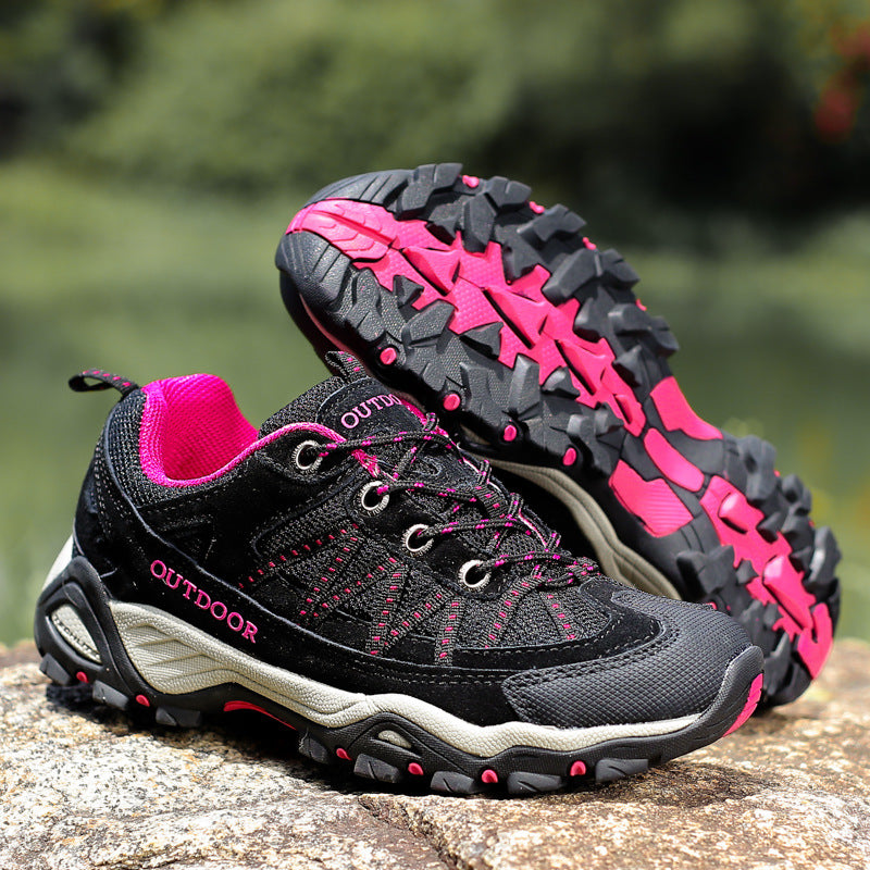 Pair of outdoor hiking shoes with lace-up fronts resting on a boulder in daylight