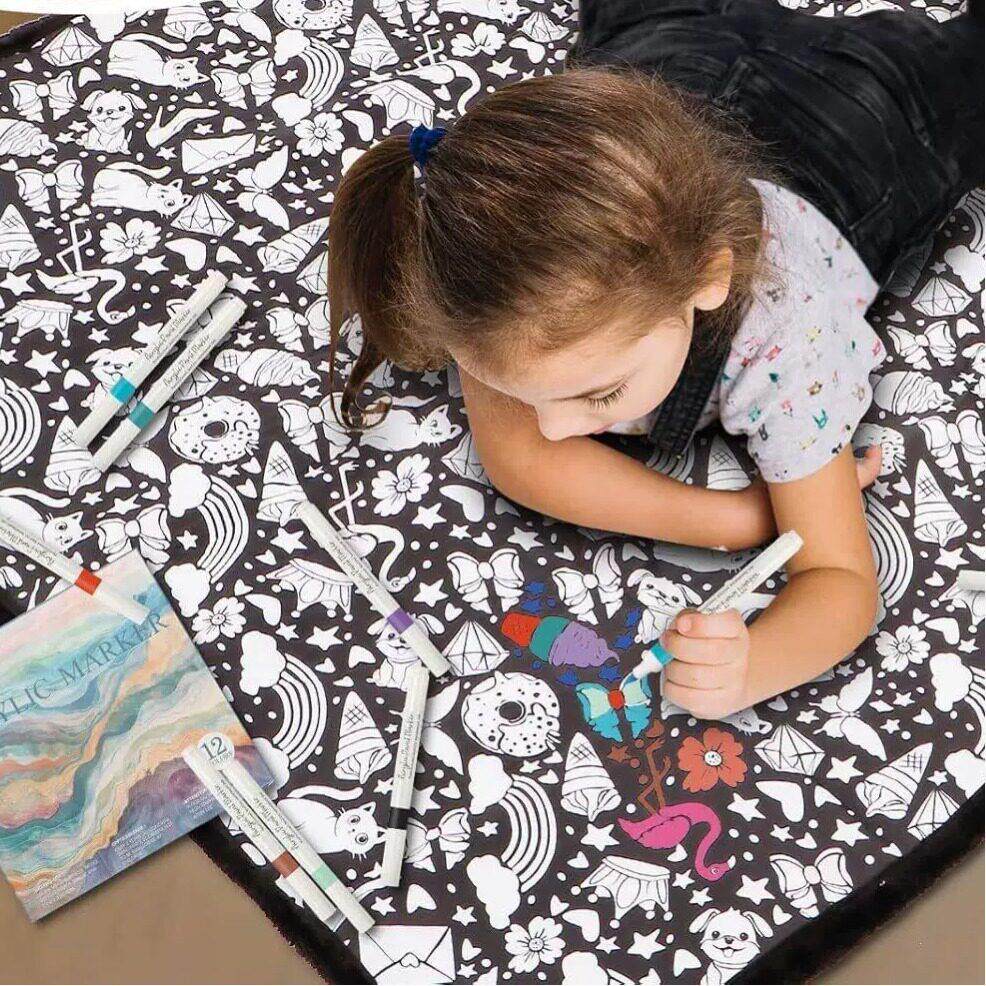 Child lying on the floor coloring the blanket beside the included coloring pen set