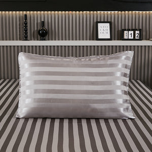 Dark gray stripe satin pillowcase on a bed with matching striped sheets