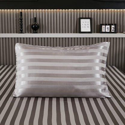 Dark gray stripe satin pillowcase on a bed with matching striped sheets