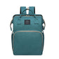 Green diaper backpack in a teal tone, front view with two top handles, a woven label and a front zip pocket