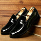 Pair of glossy black loafers with a black matte vamp and a penny strap on a wooden shelf