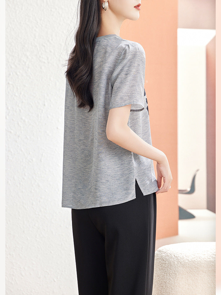 Lake Blue silk blouse with seashell motif worn seated with white trousers