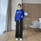 Black wide-leg pants with white drawstring ties worn with a blue sweater and white sneakers