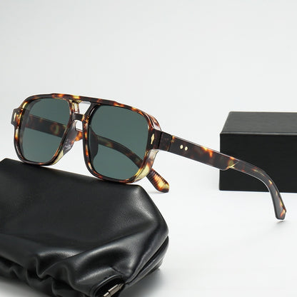 Square double bridge sunglasses with a tortoise frame and green lenses on a black case