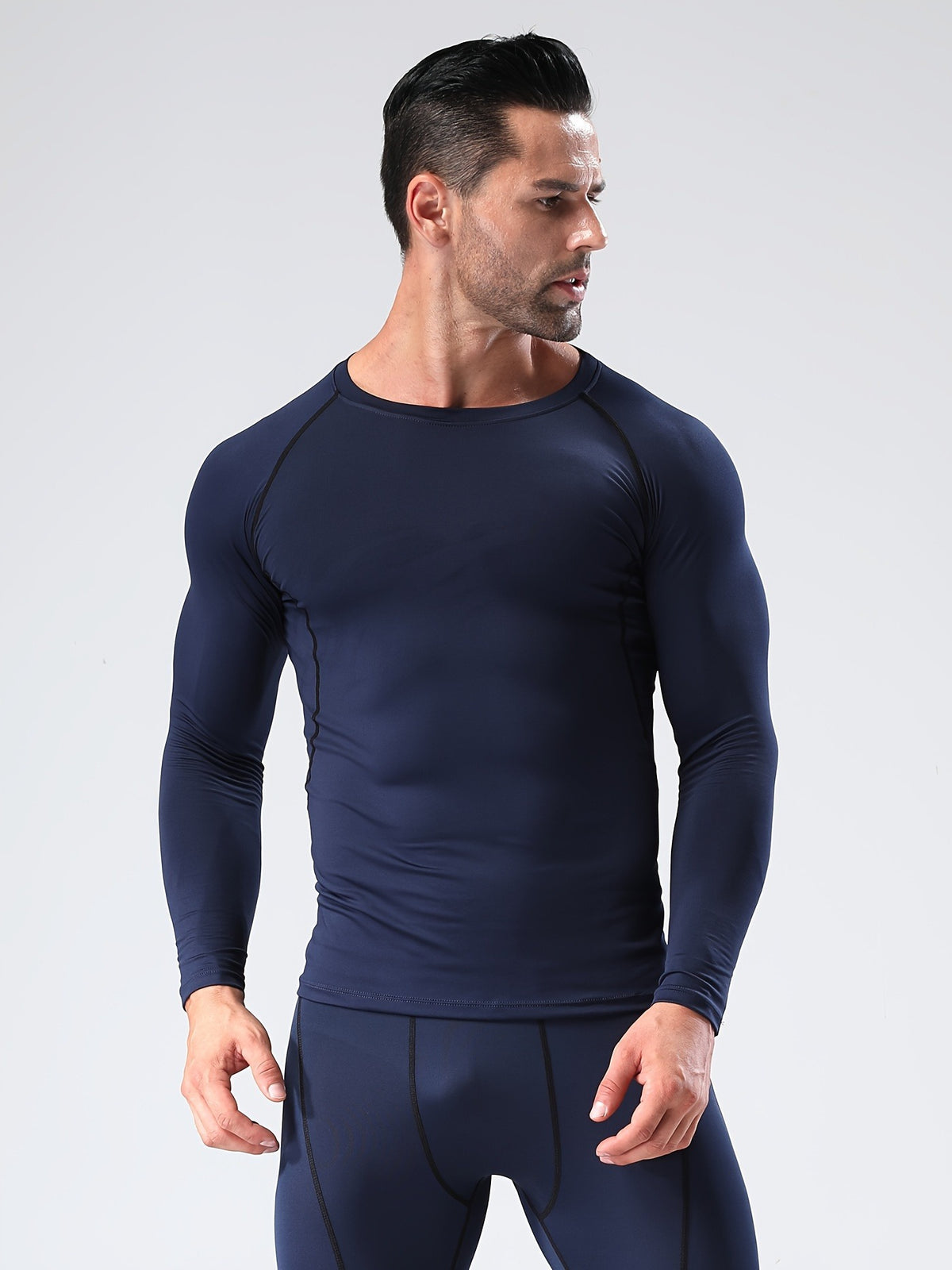Man in a navy long sleeve compression shirt with raglan sleeves, looking to the side