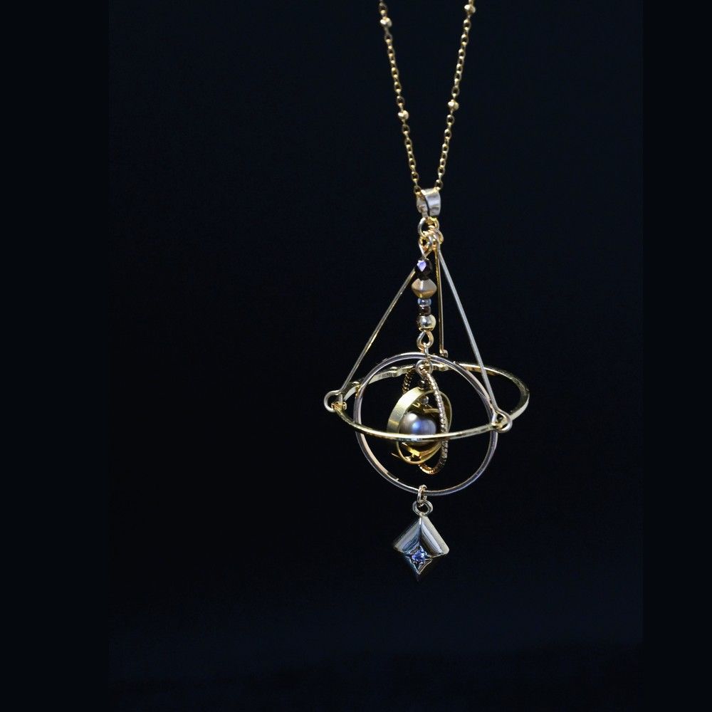 Armillary sphere pendant on a dark background, rings tilted around the central grey bead
