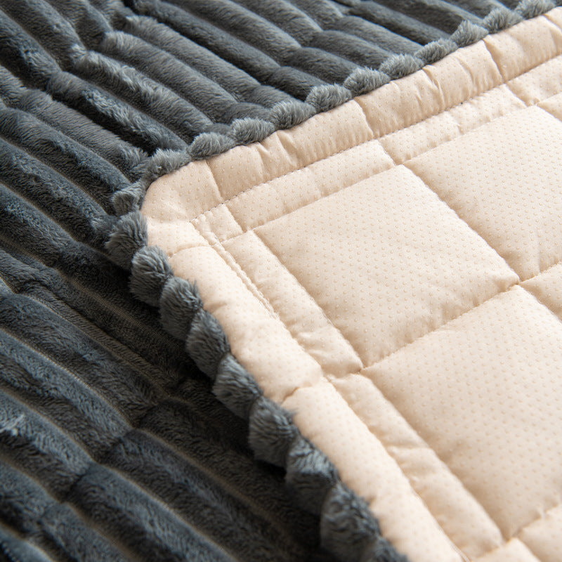 Corner of a dark gray plush sofa cover lifted to show the cream quilted dotted backing