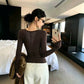 Dark brown long sleeve top seen from the back with a V shaped sheer floral lace panel on the upper back
