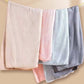 Four folded coral fleece hair towels in beige, pink, light blue and grey with a pineapple plaid texture