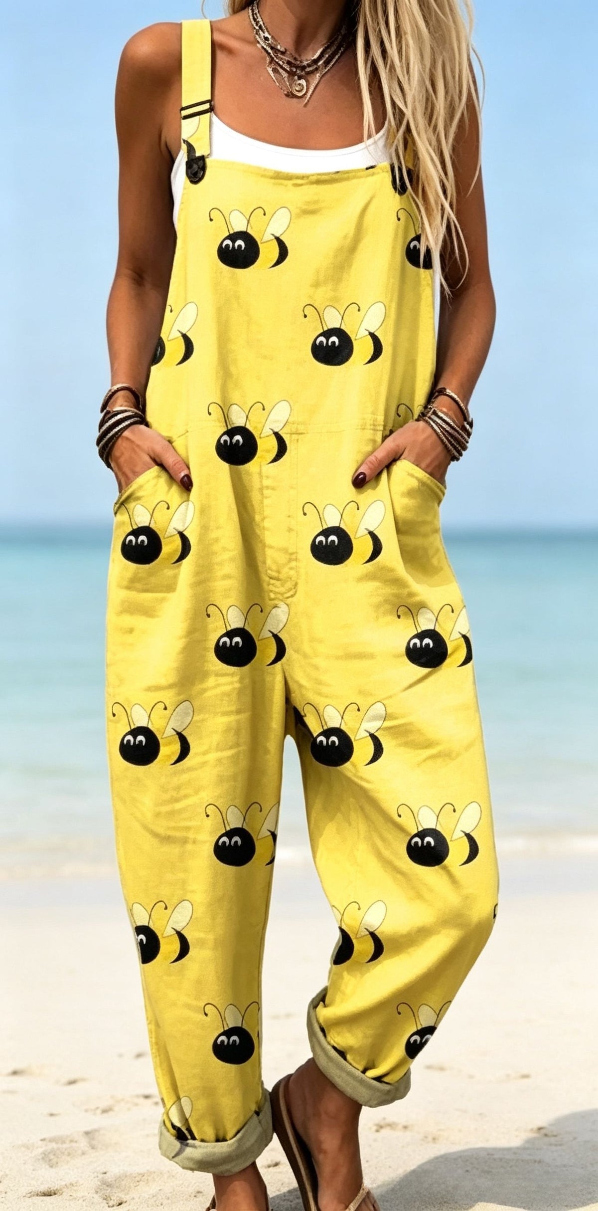 Size XL option: Yellow overalls with a black bee print, cuffed legs and front pockets on a beach