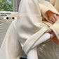 Cream fleece-lined wide-leg pants seen from the side while seated, with a cream fleece jacket and colour dots