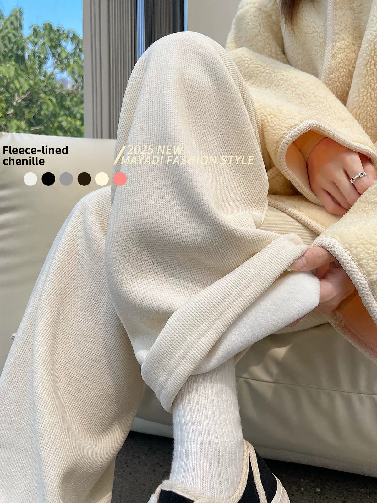 Cream fleece-lined wide-leg pants seen from the side while seated, with a cream fleece jacket and colour dots