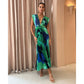Model wearing the green abstract pleated maxi dress in a lit corridor