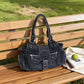 Blue washed denim shoulder bag with buckle flap resting on a park bench