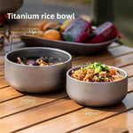 Two grey stainless steel double wall bowls on a camp table holding soup and rice