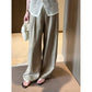 Front view of khaki wide-leg summer pants worn with a cream bag and sandals