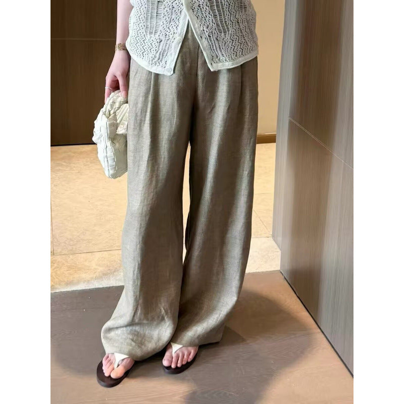 Front view of khaki wide-leg summer pants worn with a cream bag and sandals
