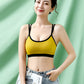 Model in a yellow bra top with black trim and a scooped neckline against a green backdrop