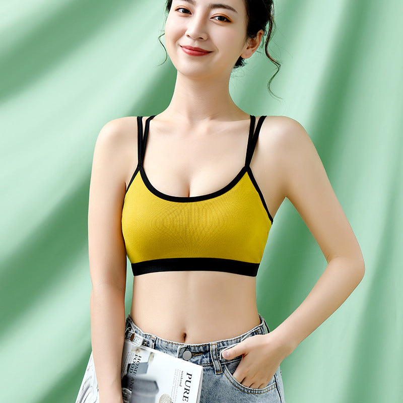 Model in a yellow bra top with black trim and a scooped neckline against a green backdrop