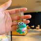 Cartoon dinosaur charm attached to a backpack loop and zip