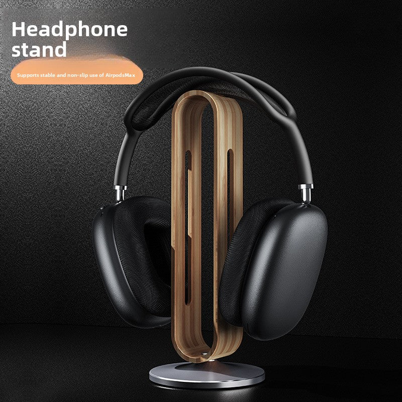 Gray walnut wood grain headphone stand holding black over ear headphones on a dark desk