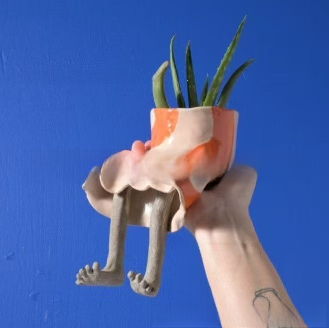 Resin lower body planter in an orange dress with bare legs holding an aloe plant