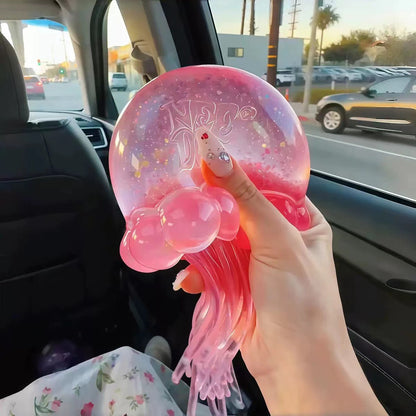 Pink NeeDoh Jelly Squish jellyfish held in hand with glitter gel bell and long ribbon tentacles