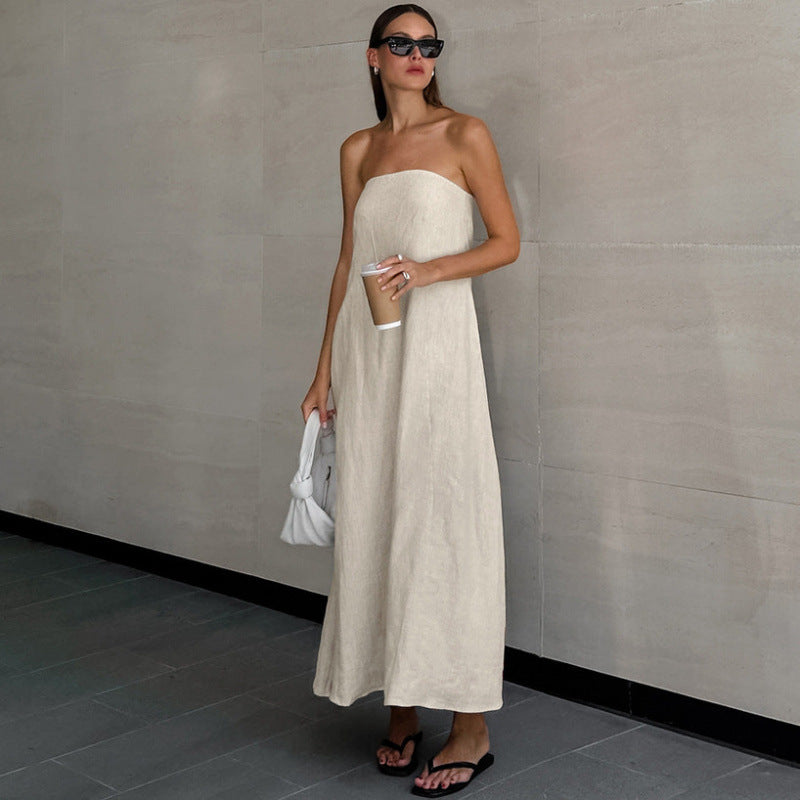 Woman wearing khaki strapless linen maxi dress with flat sandals outdoors