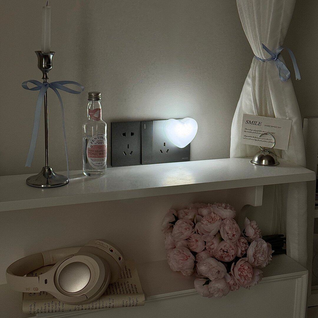 White heart night light sitting flat against the wall sockets at night