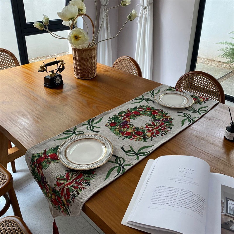 Christmas table runner with holly wreath pattern on a beige ground on a wooden table, 33x280 cm option