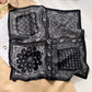 Black and white paisley bandana printed square scarf with a satin sheen and hemmed edges, shown displayed